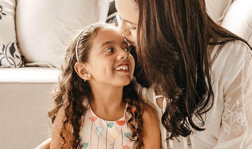 mom kissing daughter on forehead